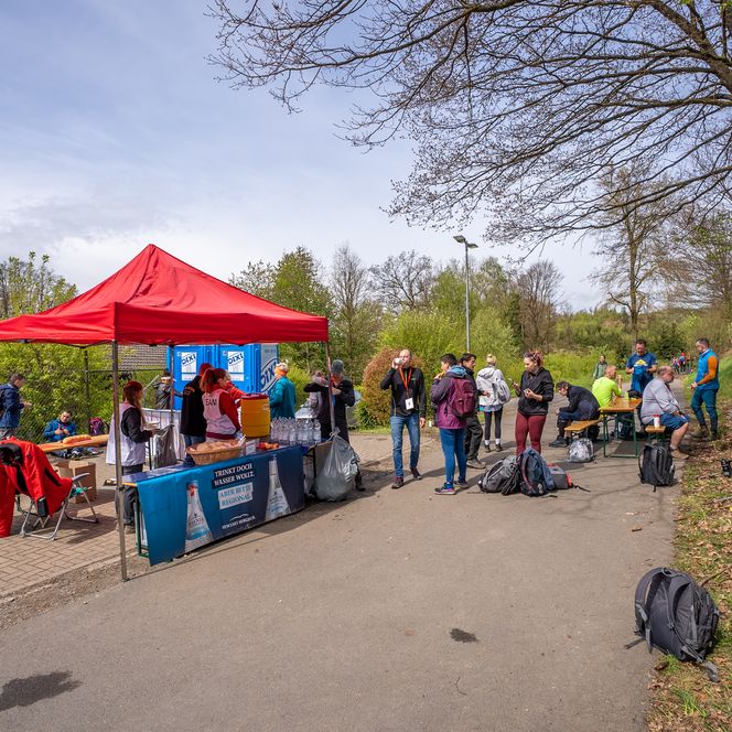 Menschen versammeln sich um einen Stand unter einem roten Pavillon im Freien.