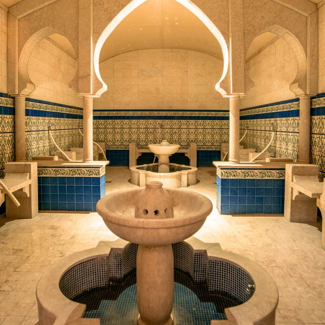 <p>Prächtiger, orientalisch gestalteter Hamam mit zentralem Brunnen und kunstvollen Fliesenmustern.</p>
