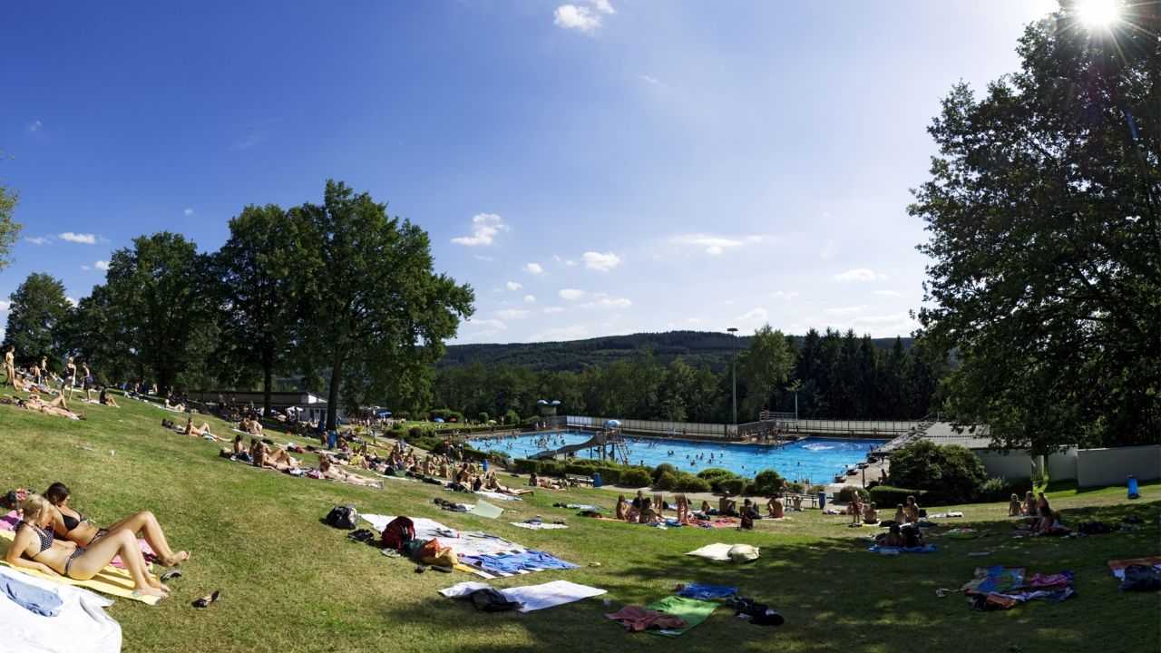 Blick über die Liegewiese zum Becken im Freibad Engelskirchen, Menschen auf Liegewiese