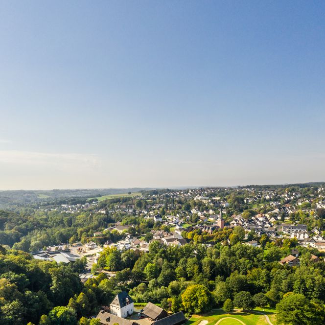 <p>Luftbild von Much: Golfplatz im Vordergrund, umliegende Landschaft und Siedlungen im Hintergrund.</p>