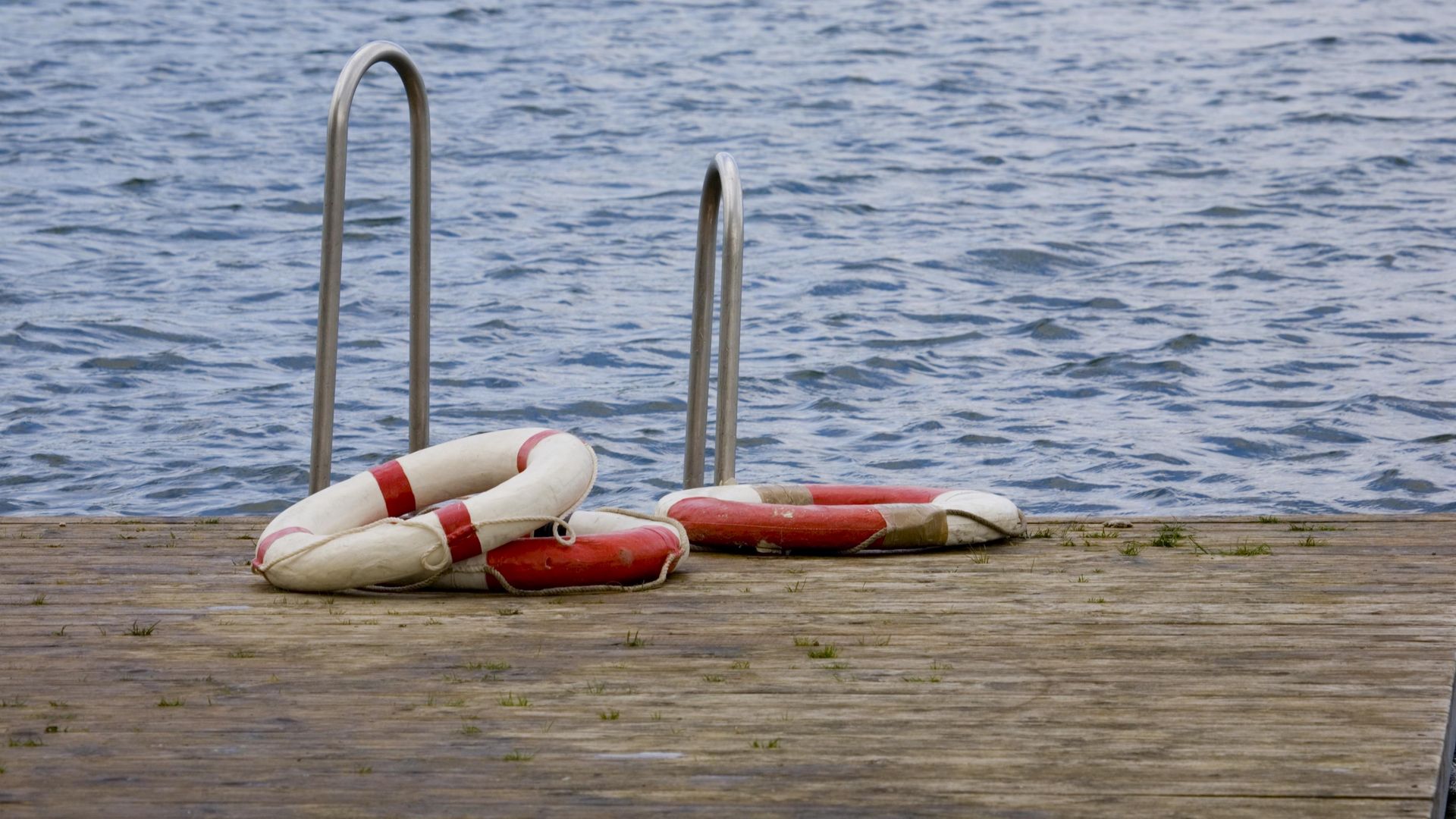 zwei Rettungsringe liegen auf einem Badesteg vor der Treppe ins Wasser