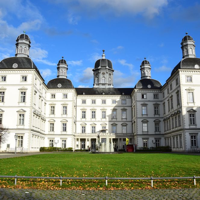 Schloss Bensberg in Bergisch Gladbach; imposantes Barockgebäude mit gepflegtem Rasen und wolkigen Himmel.