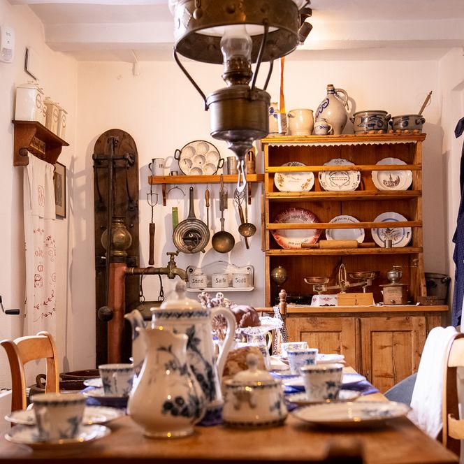 Alte Küche mit Geschirr, Töpfen, traditionellem Charme und blauen Dekorelementen im Landhausstil.