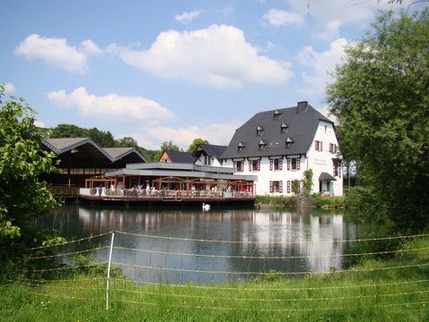 Blick über den Teich auf ein Café mit Biergarten in Herrenstrunden