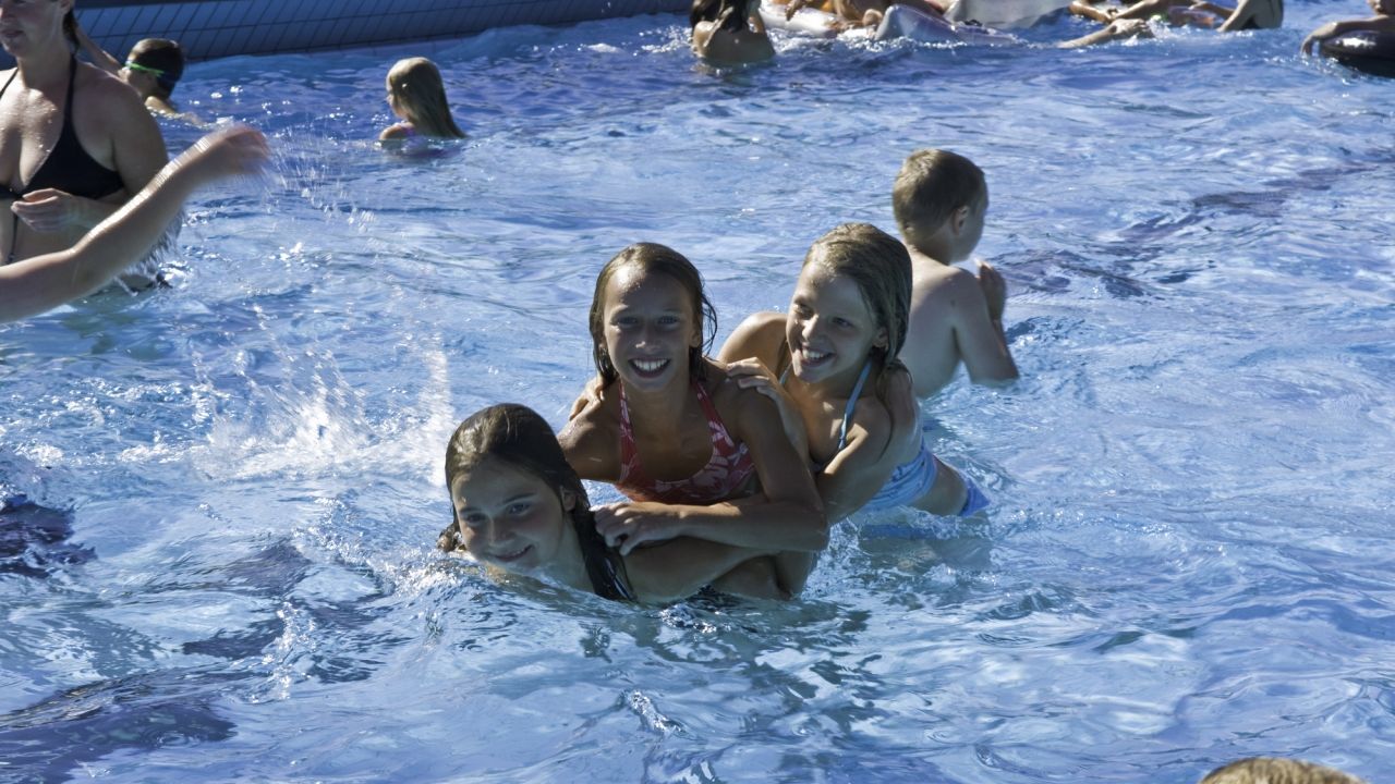 vier Kinder spielen im Schwimmbecken im Freibad Engelskirchen