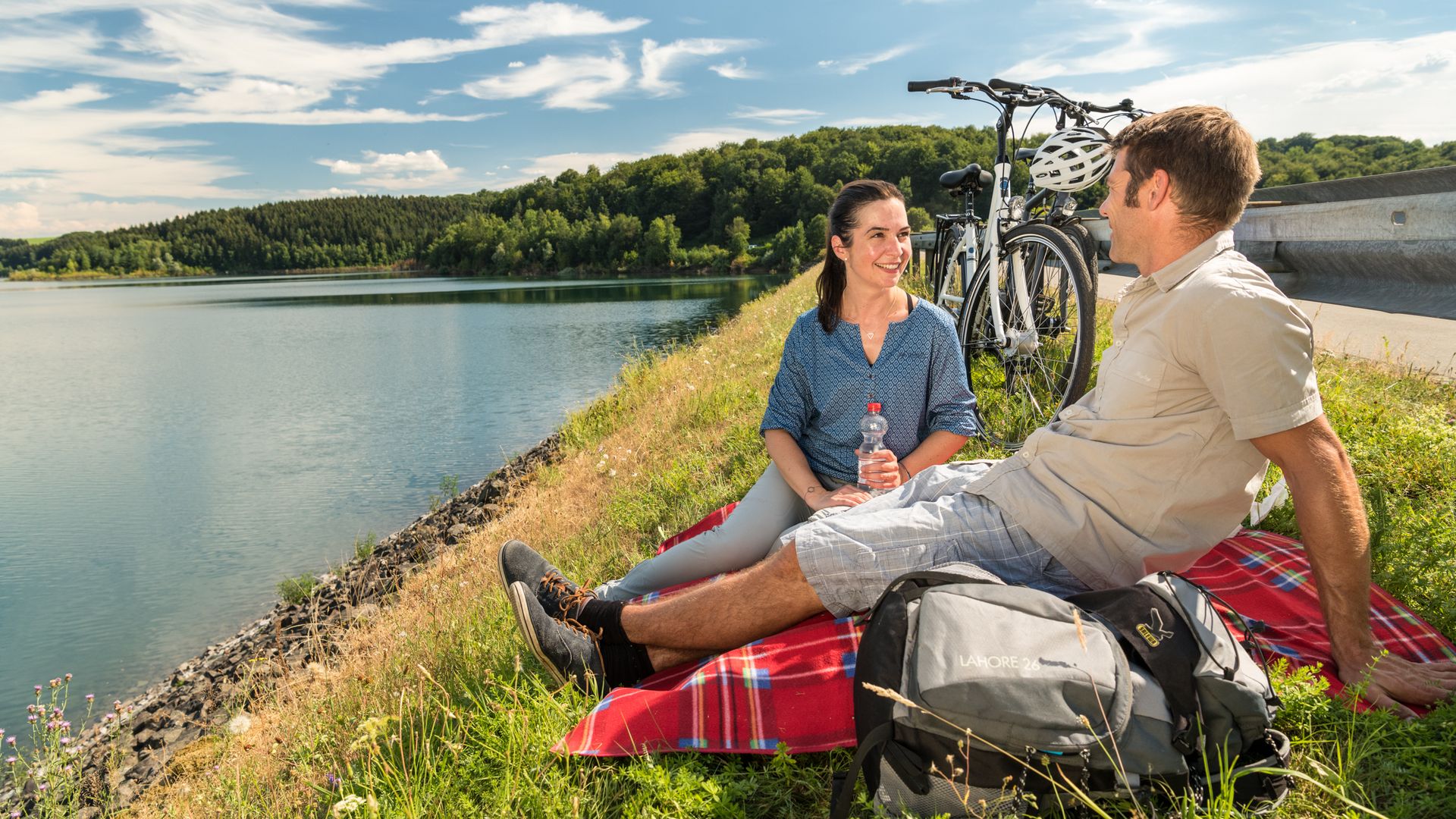 Pärchen mit Rädern macht Picknick am Staudamm einer Talsperre