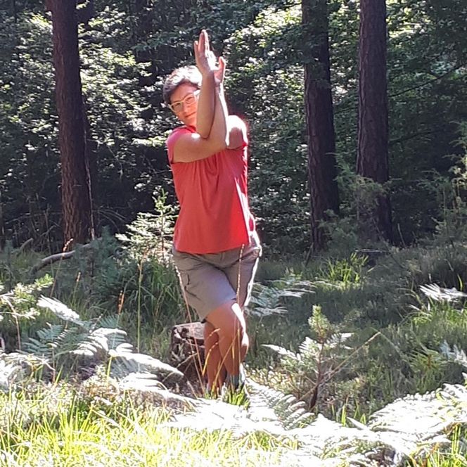 Eine Frau macht eine Yogaübung im Wald.