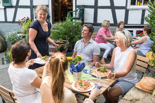 Kellnerin serviert freundlich lächelnd Essen im Biergarten