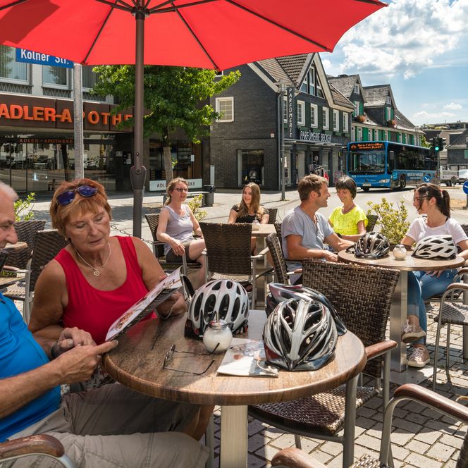 Personen genießen an einem sonnigen Tag in einem Straßencafé in Wermelskirchen ihre Zeit.