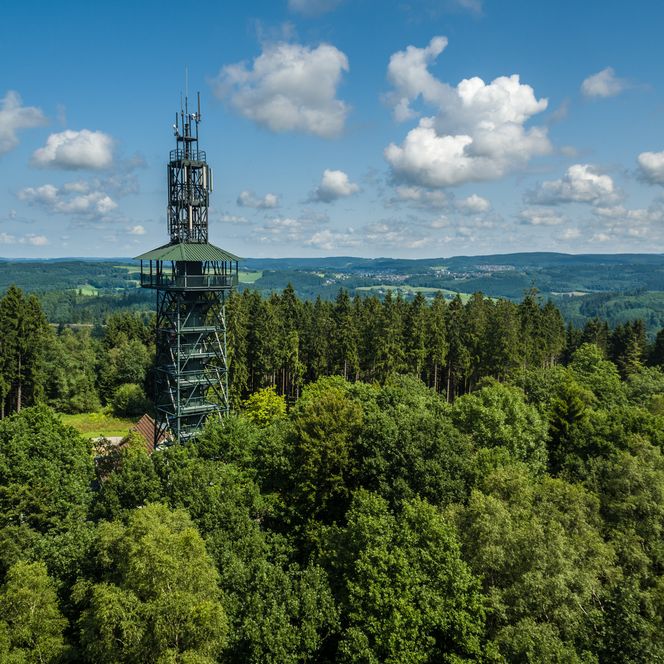 Aussichtsturm im Wald Gummersbachs, umgeben von Bäumen mit bewölktem Himmel, Panoramablick in die Ferne.