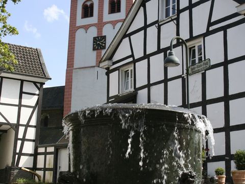 Hexenbrunnen vor der Kirche und Fachwerkhäusern im Ortskern von Odenthal