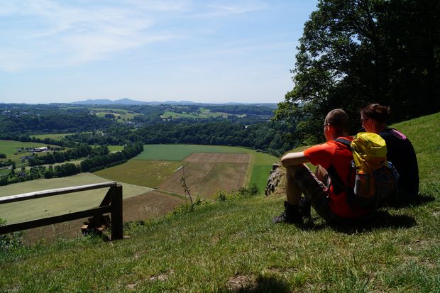 Pärchen sitzt auf einer Wiese auf einer Anhöhe mit Ausblick ins Siegtal