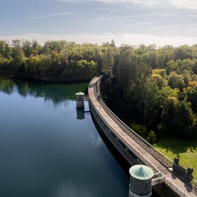 Staumauer der Neyetalsperre in Wipperfürth, umgeben von Wald und reflektierendem Wasser.