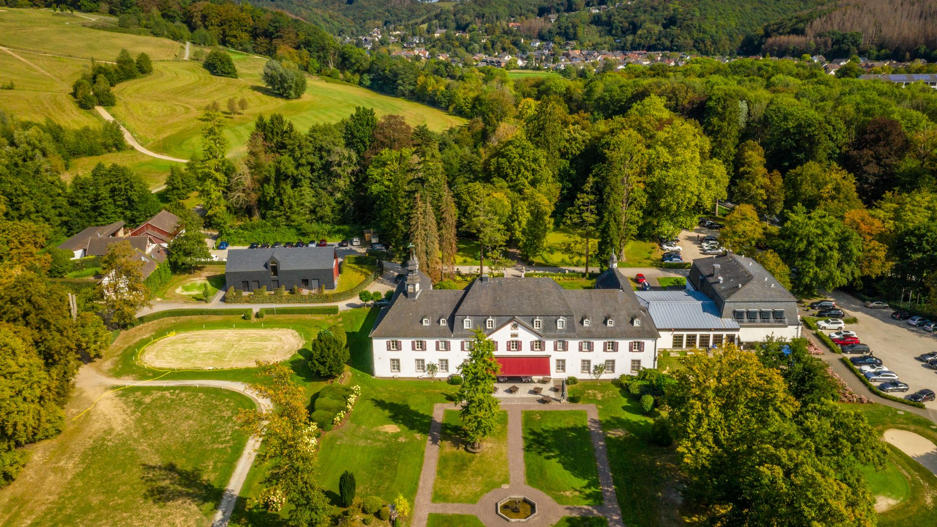 Luftaufnahme eines weißen Schlosses inmitten grüner Wiesen und Wälder-