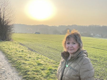 Portraitaufnahme der Gästeführerin Sylvia Bensch vor einer grünen Wiese.