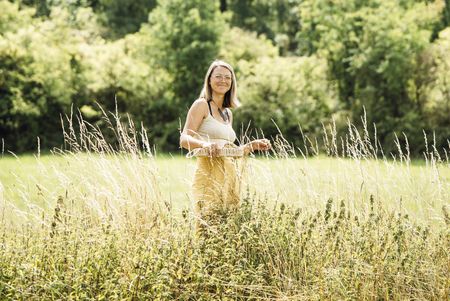 Foto der Gästeführerin Tine Knauft in einer Wiese mit hohem Gras. Sie hält ein Tablett in der Hand.