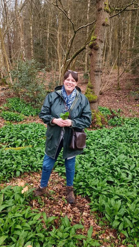 Aufnahme der Gästeführerin Astrid Saubert im Wald mitten in grünen Bärlauch-Pflanzen. 