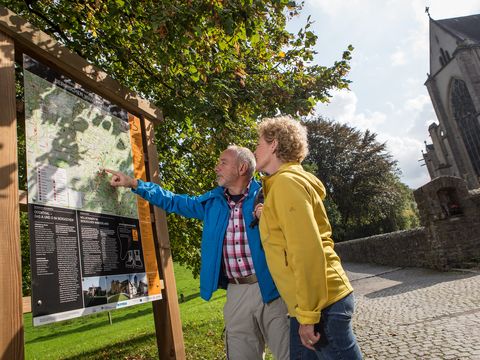 Ein Paar in Wadnerausrüstung steht vor einer Infotafel und schaut sich die Karte an