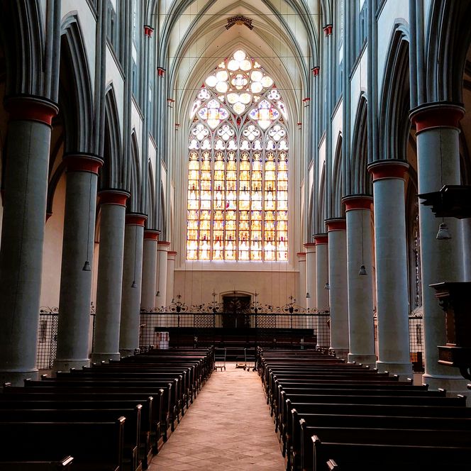 Eine beeindruckende gotische Kathedrale mit großen, detailreichen Buntglasfenstern, die leuchten.
