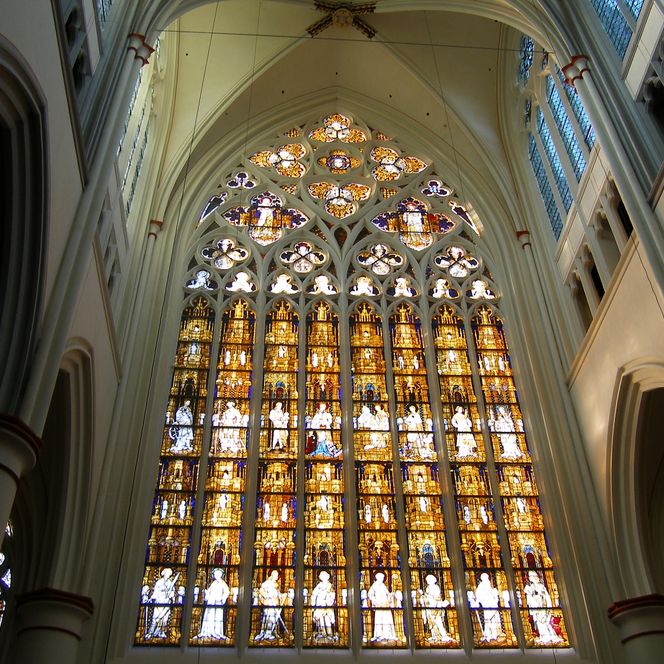 Eine beeindruckende gotische Kathedrale mit großen, detailreichen Buntglasfenstern, die leuchten.