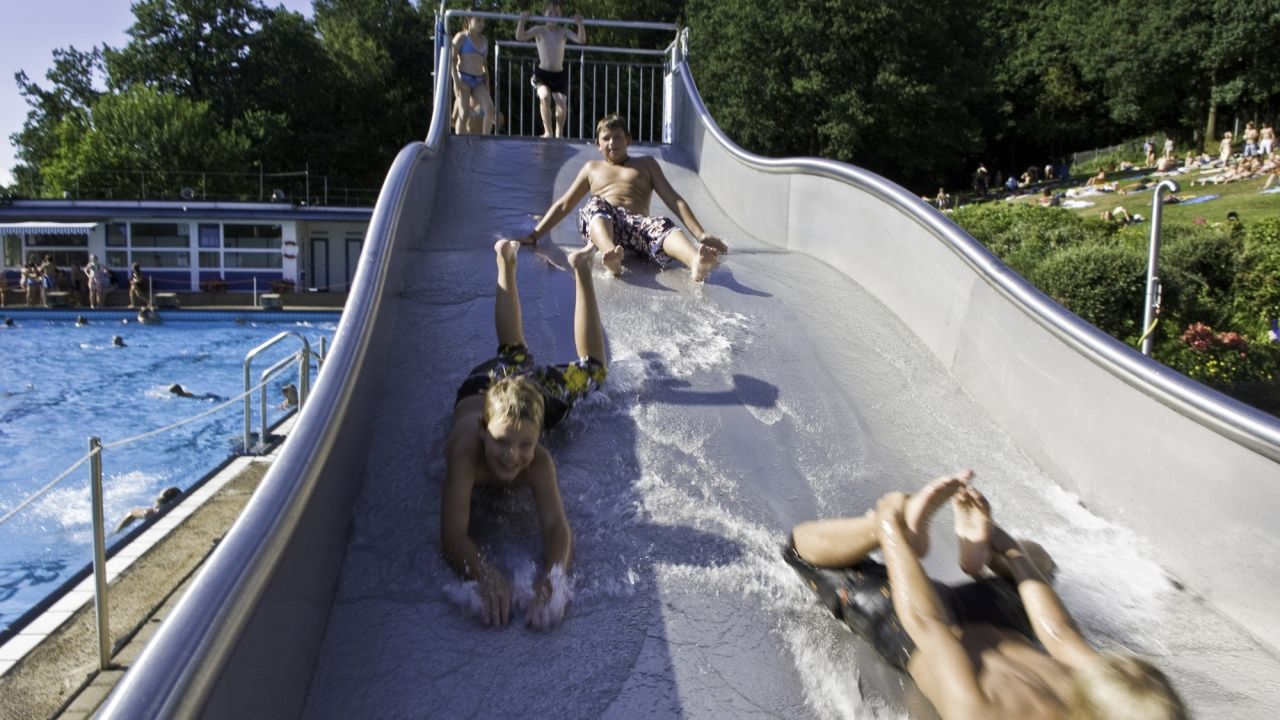 Kinder auf einer breiten Wasserrutsche im Freibad Engelskirchen