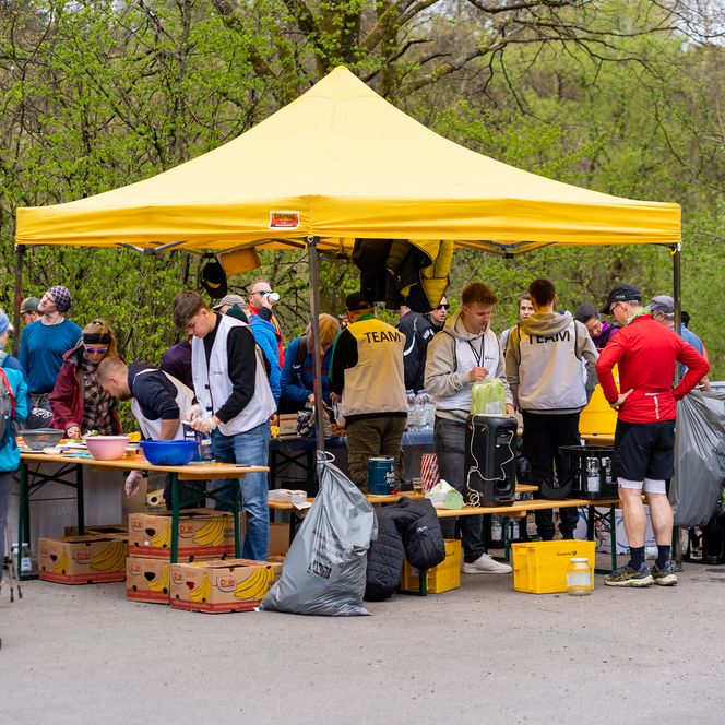 Ein gelbes Zelt mit Helfenden, welches als Erfrischungsstation für Wanderer dient.
